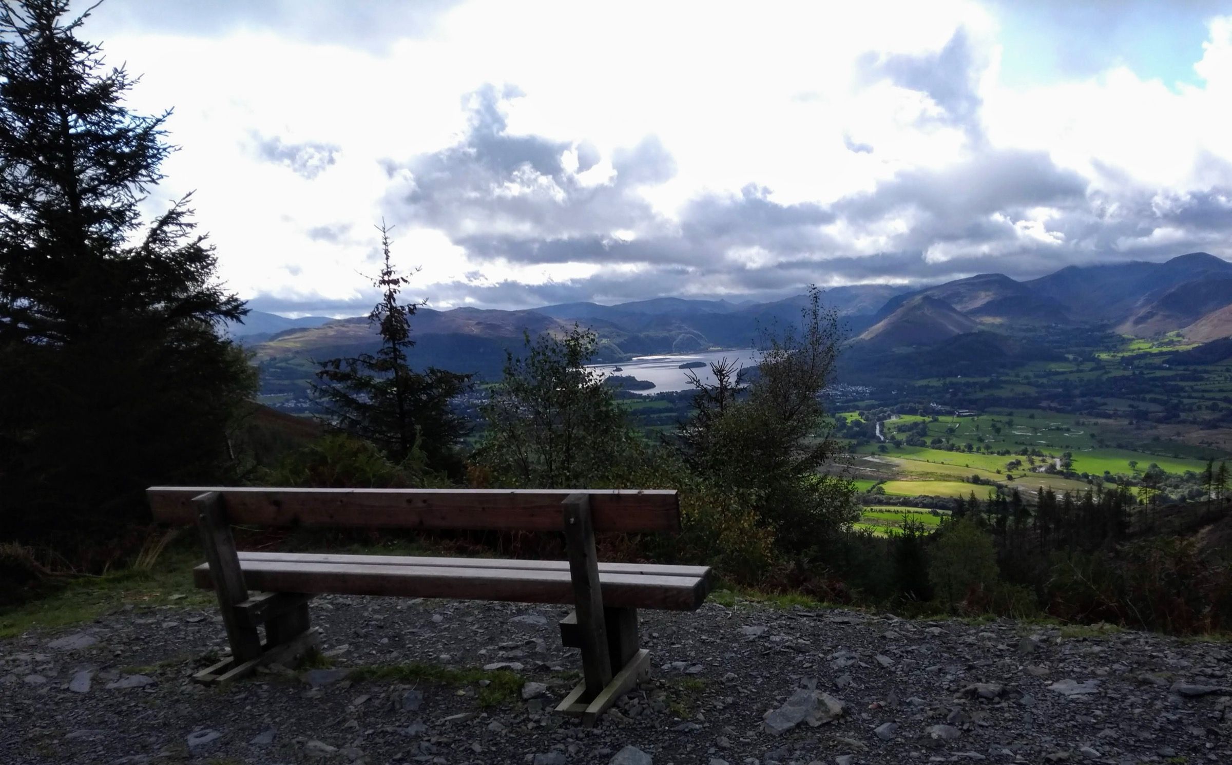 A wooden bench looking out over Derwentwater and the northern fells under a broken sky