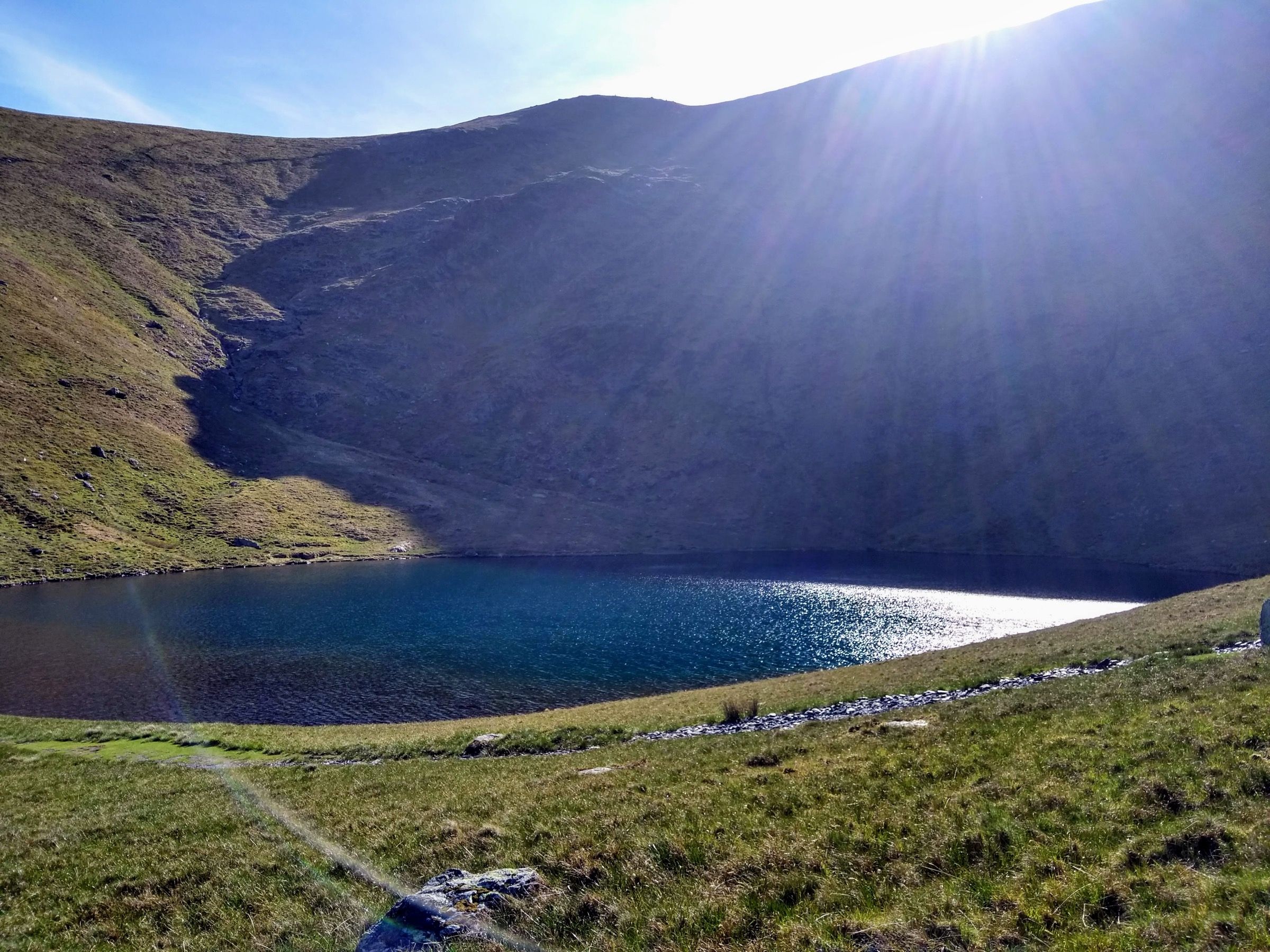 Scales Tarn below the dark slopes of Blencathra, with sun breaking over the ridge